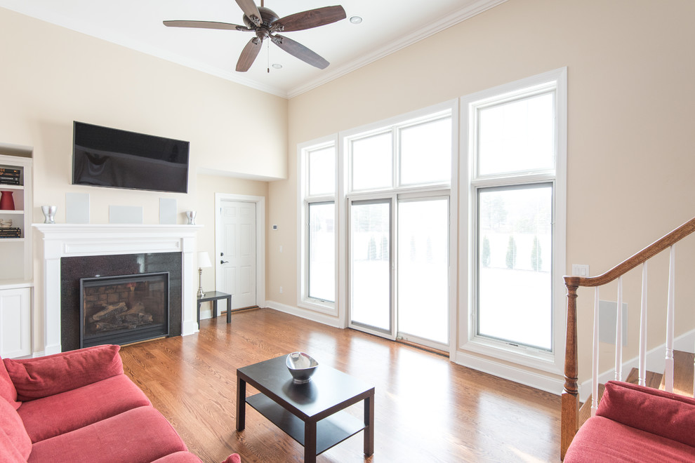 Mid-sized elegant enclosed medium tone wood floor family room photo in Atlanta with beige walls, a standard fireplace, a tile fireplace and a wall-mounted tv