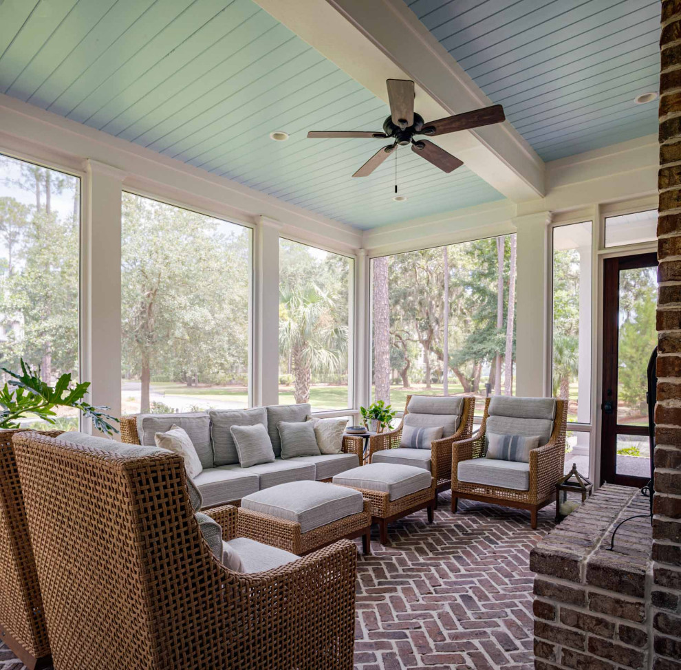 This is an example of a brick screened-in side porch design in Other with a roof extension.