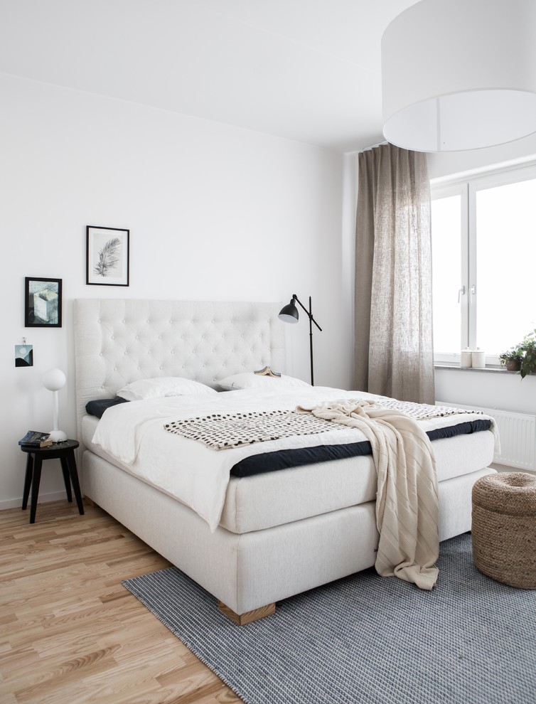 Photo of a mid-sized scandinavian master bedroom in Malmo with white walls, light hardwood floors and no fireplace.