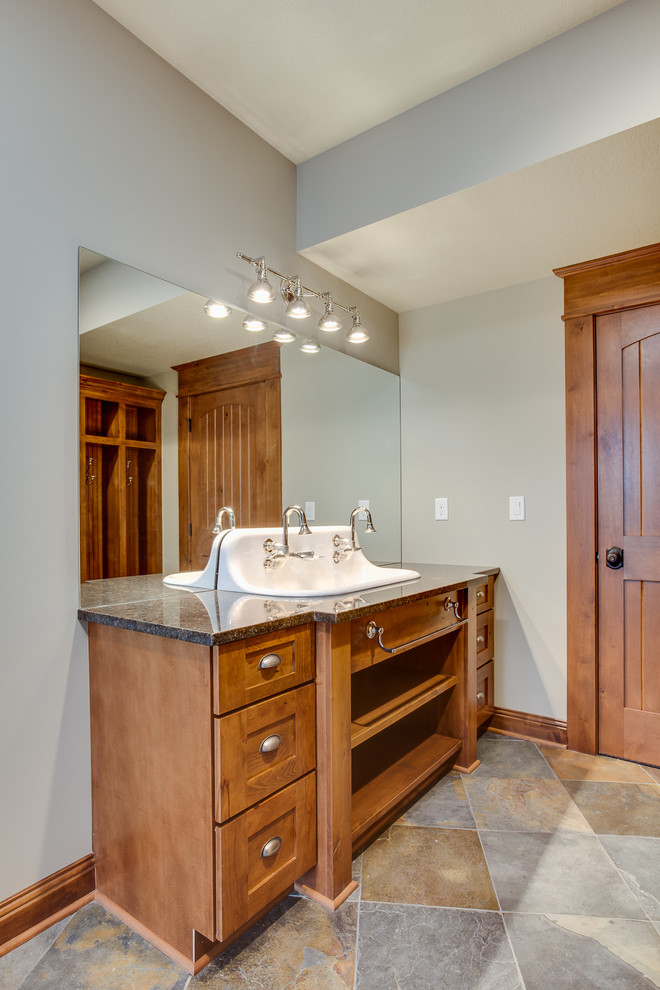 Example of a large mountain style multicolored tile and stone tile slate floor doorless shower design with a console sink, flat-panel cabinets, medium tone wood cabinets, granite countertops, a two-piece toilet and beige walls