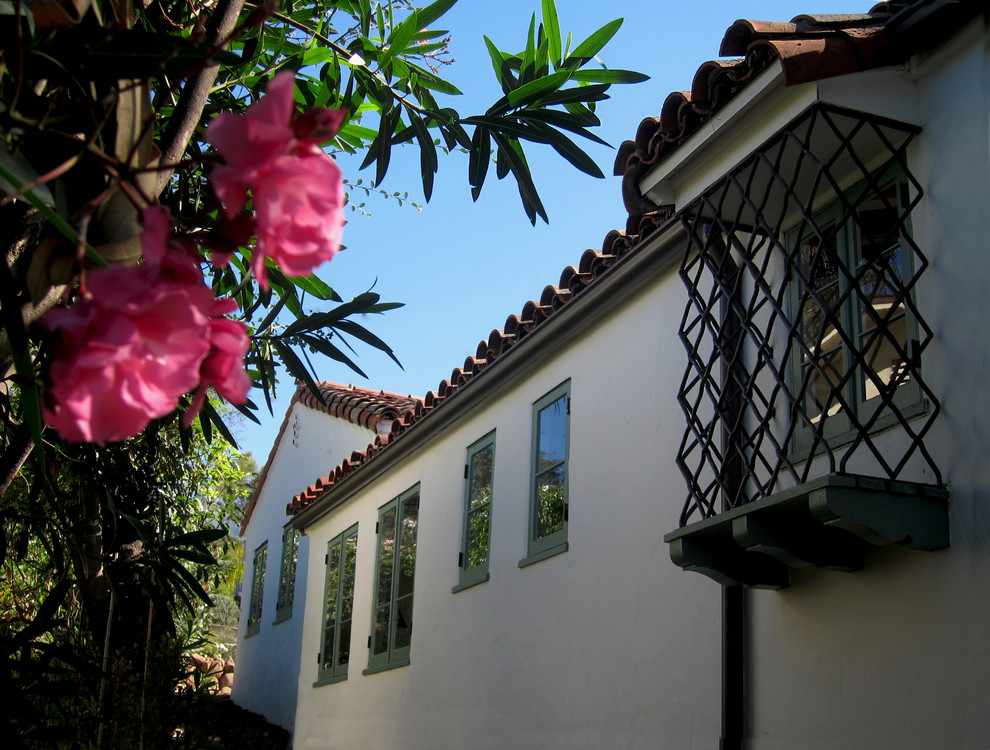 Design ideas for a mid-sized mediterranean one-storey stucco white house exterior in Santa Barbara with a clipped gable roof and a tile roof.