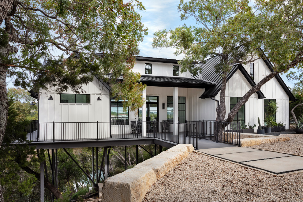 Example of a mid-sized minimalist white one-story wood and board and batten house exterior design in Austin with a shed roof, a metal roof and a black roof