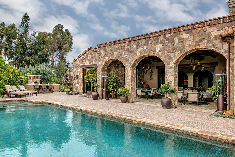 Expansive mediterranean backyard rectangular infinity pool in San Diego with a hot tub and natural stone pavers.