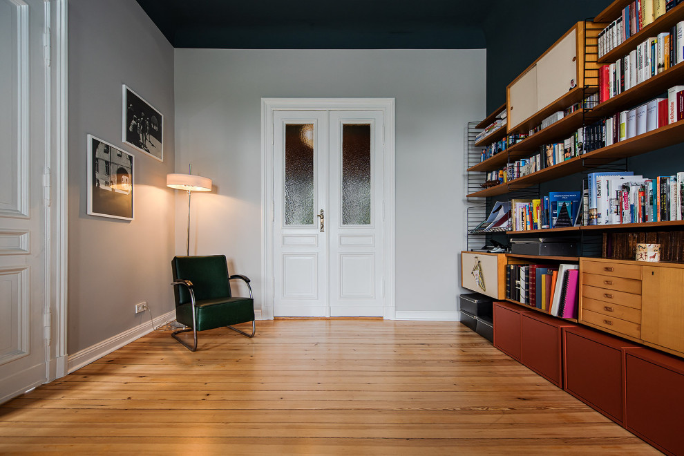 Inspiration för ett stort eklektiskt arbetsrum, med ett bibliotek, blå väggar, ljust trägolv, ett fristående skrivbord och brunt golv