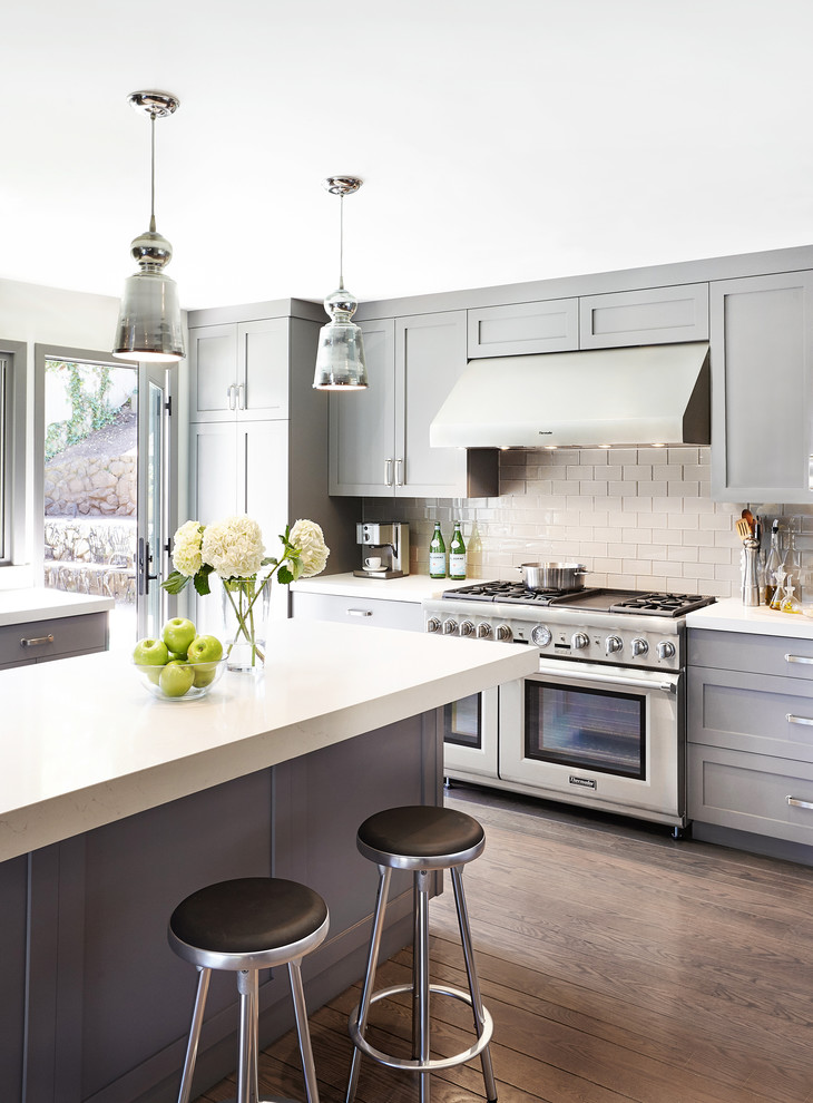 This is an example of a transitional kitchen in San Francisco with shaker cabinets, grey cabinets, grey splashback, glass tile splashback, stainless steel appliances, medium hardwood floors and with island.