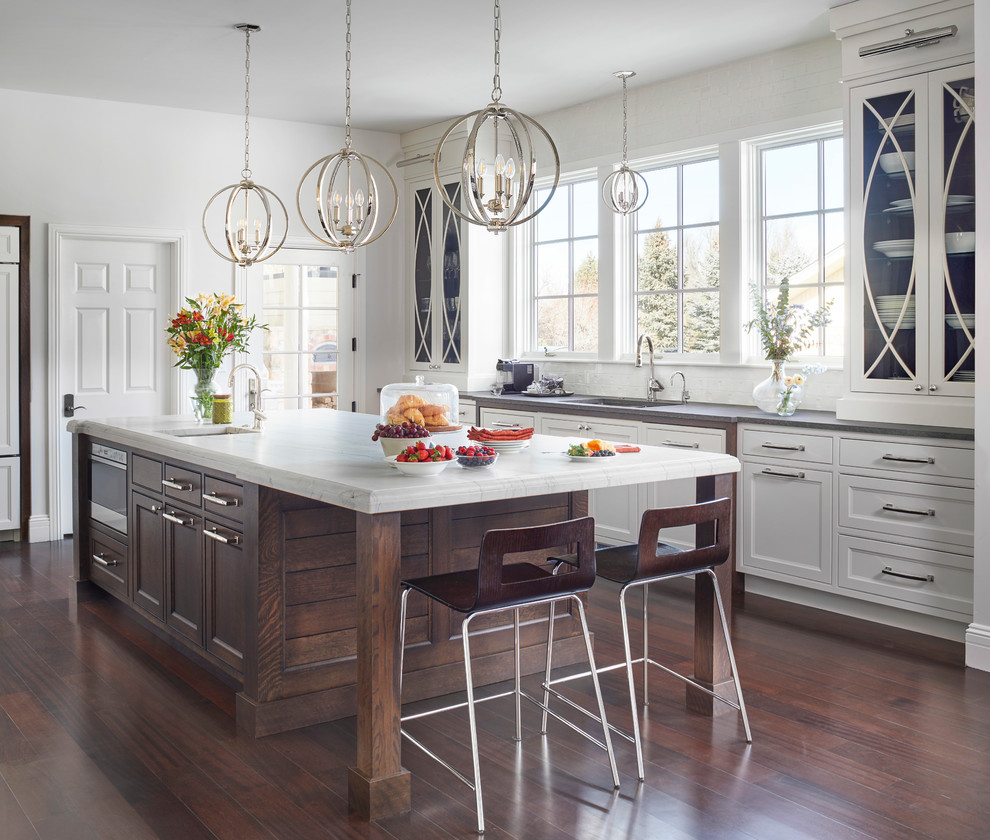 Design ideas for an expansive transitional galley eat-in kitchen in Denver with an undermount sink, recessed-panel cabinets, white cabinets, quartzite benchtops, white splashback, ceramic splashback, panelled appliances, dark hardwood floors, with island, brown floor and white benchtop.