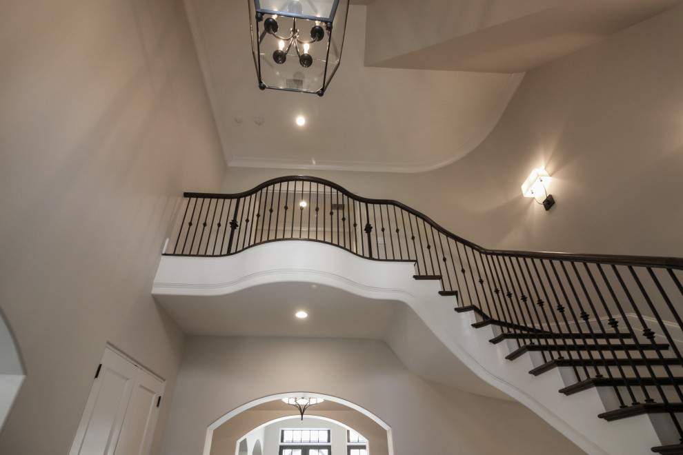 Diseño de escalera suspendida clásica grande con escalones de madera, contrahuellas de madera pintada y barandilla de metal