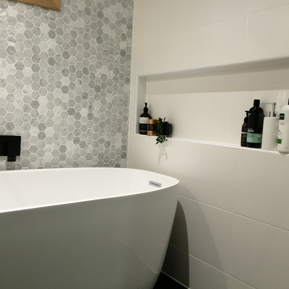 Photo of a small contemporary wet room bathroom in Brisbane with a freestanding tub, white tile, ceramic tile, multi-coloured walls, ceramic floors, black floor, an open shower, furniture-like cabinets, brown cabinets, an integrated sink, solid surface benchtops and white benchtops.