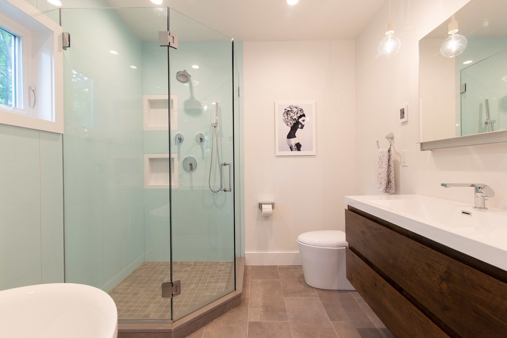 Design ideas for a mid-sized contemporary bathroom in Other with flat-panel cabinets, dark wood cabinets, a japanese tub, a corner shower, a one-piece toilet, green tile, white walls, porcelain floors, an integrated sink, solid surface benchtops, grey floor, a hinged shower door and white benchtops.