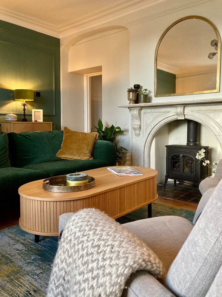 Medium sized classic formal enclosed living room in Buckinghamshire with green walls, medium hardwood flooring, a wood burning stove, a stone fireplace surround, no tv, beige floors, panelled walls and a chimney breast.