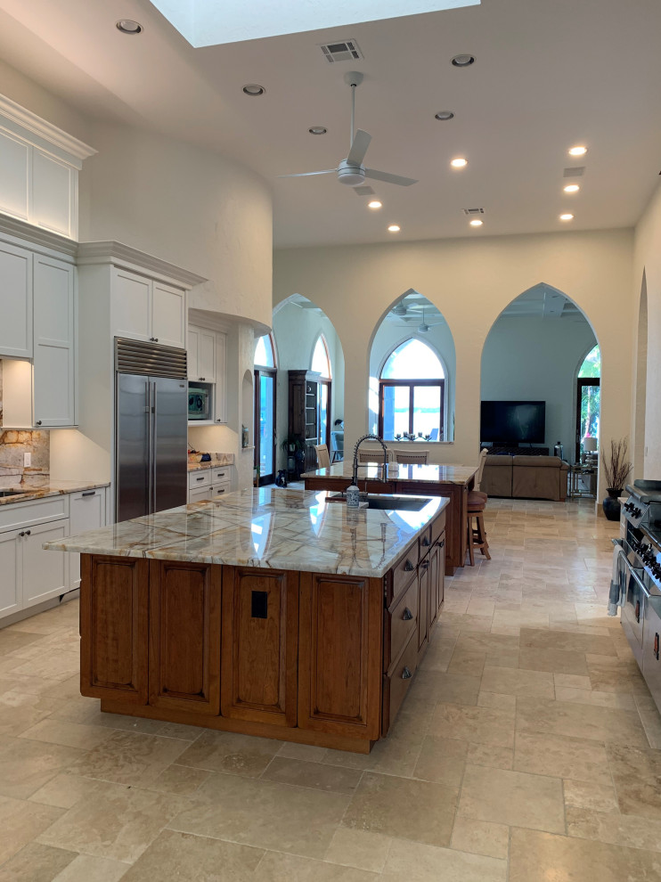 Inredning av ett klassiskt flerfärgad flerfärgat kök och matrum, med en enkel diskho, skåp i shakerstil, vita skåp, rostfria vitvaror, flera köksöar och beiget golv