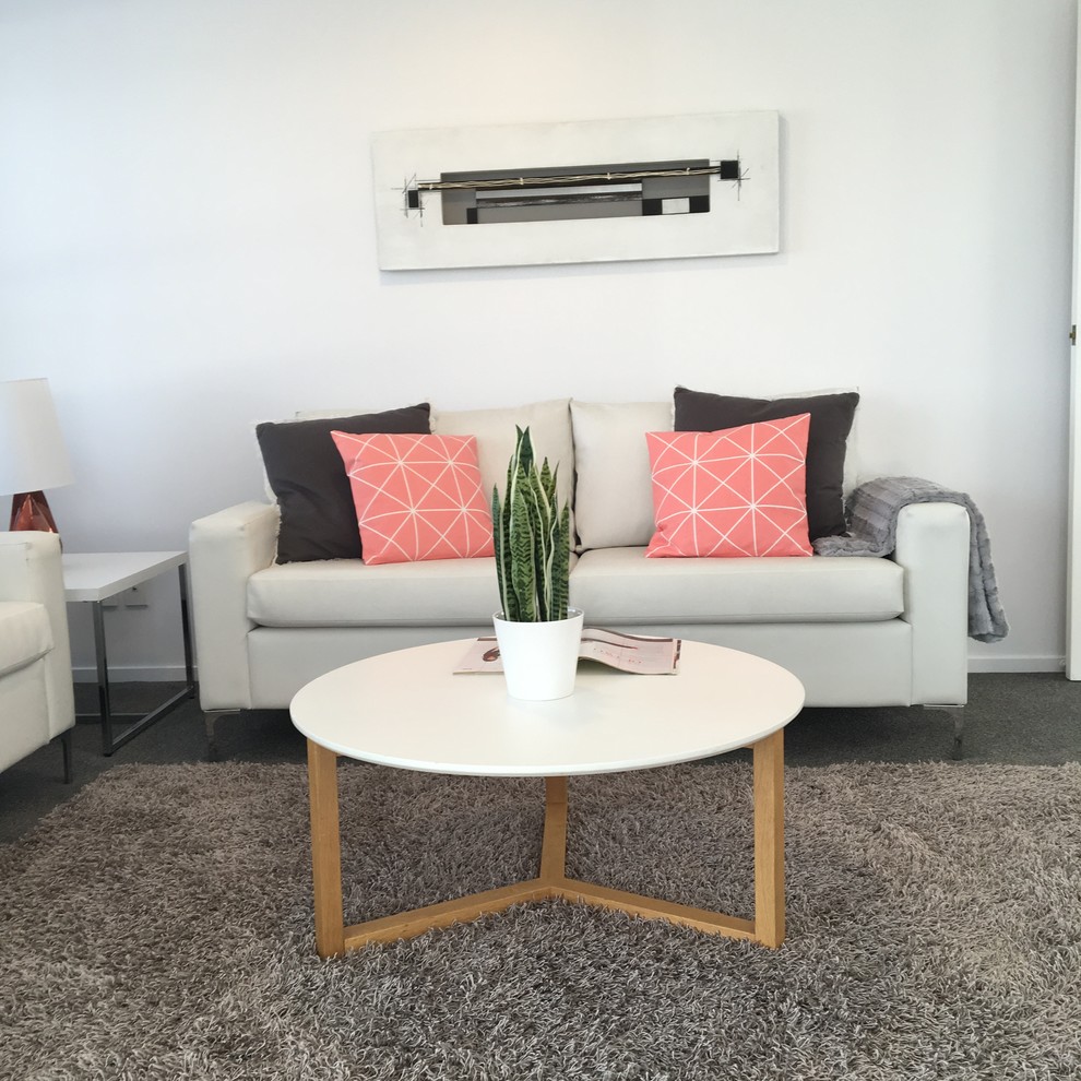This is an example of a small modern open concept living room in Auckland with white walls, carpet, no fireplace and grey floor.