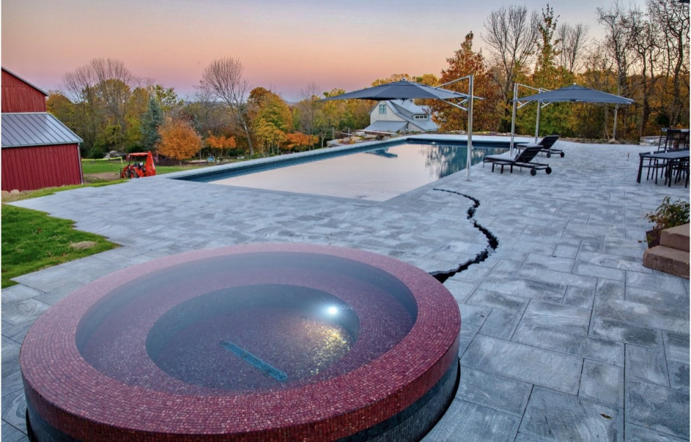 Ejemplo de casa de la piscina y piscina alargada vintage grande rectangular en patio trasero con granito descompuesto