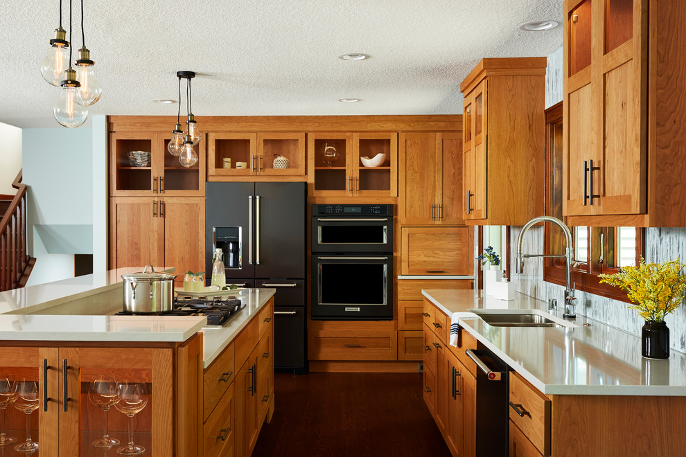 This is an example of a transitional kitchen with a double-bowl sink, shaker cabinets, medium wood cabinets, black appliances, dark hardwood floors and with island.