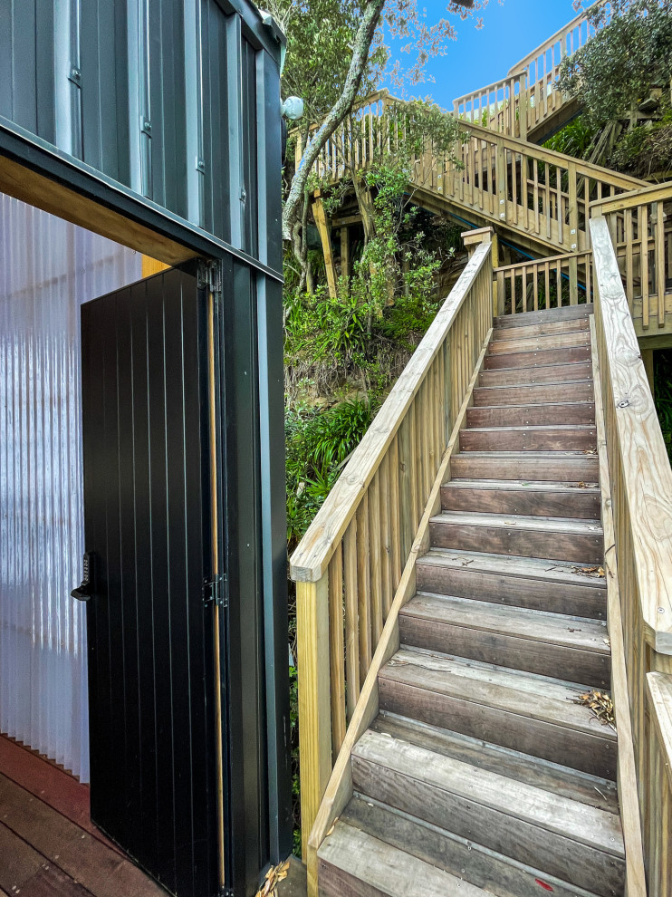 This is an example of an expansive beach style wood staircase in Auckland with wood railing and wood walls.