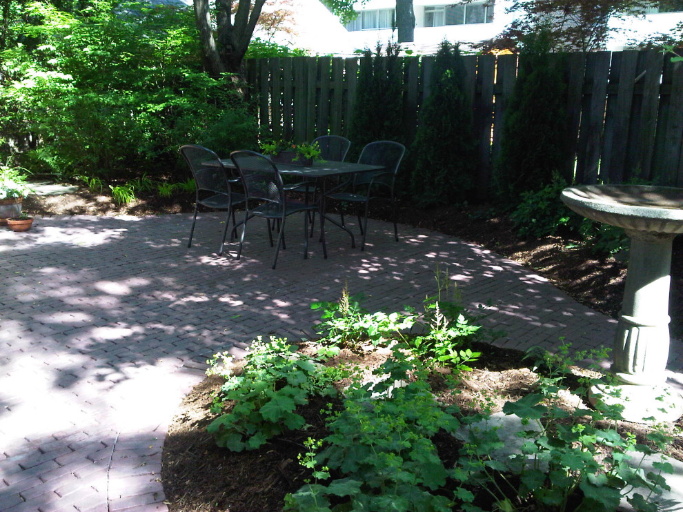 На фото: тенистый, летний участок и сад среднего размера на заднем дворе с клумбами и мощением клинкерной брусчаткой