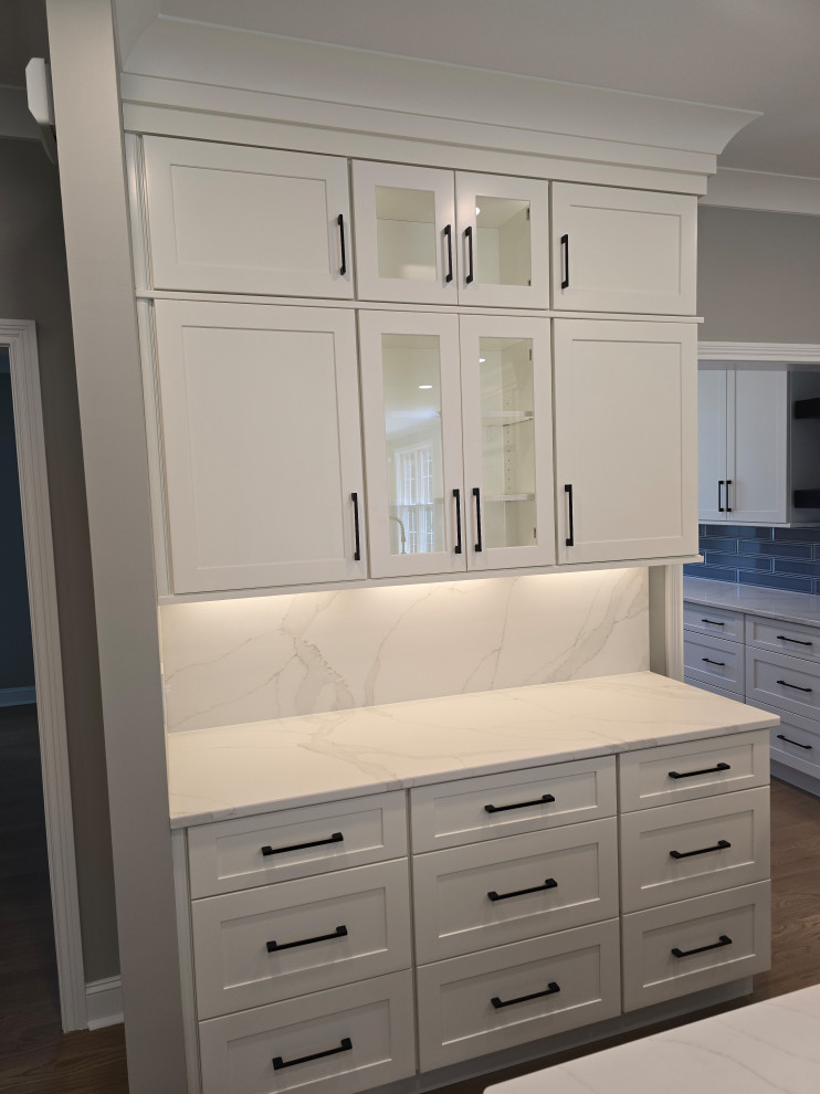 Example of a large minimalist l-shaped medium tone wood floor and brown floor open concept kitchen design with shaker cabinets, white cabinets, quartz countertops, white backsplash, quartz backsplash and white countertops