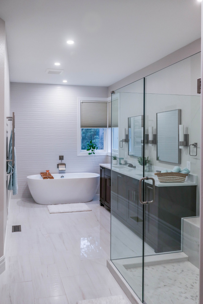 Photo of a contemporary ensuite bathroom in Seattle with freestanding cabinets, dark wood cabinets, a freestanding bath, a corner shower, a one-piece toilet, white tiles, ceramic tiles, white walls, ceramic flooring, a submerged sink, marble worktops, white floors, a hinged door, white worktops, a shower bench, double sinks and a freestanding vanity unit.