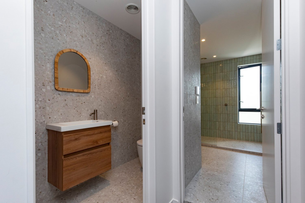 This is an example of a medium sized modern ensuite bathroom in Perth with freestanding cabinets, dark wood cabinets, a walk-in shower, green tiles, stone tiles, porcelain flooring, a vessel sink, engineered stone worktops, grey floors, an open shower, white worktops, a single sink, a floating vanity unit and wood walls.
