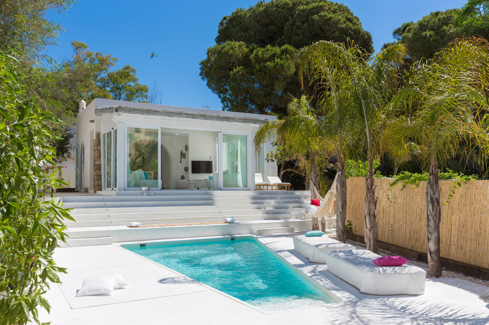 Photo of a mediterranean front yard custom-shaped lap pool in Malaga with a pool house and concrete slab.
