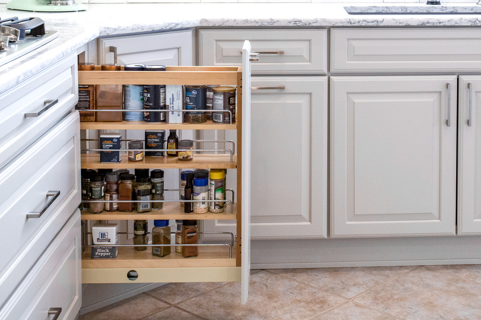 Inspiration for a mid-sized transitional single-wall ceramic tile and beige floor eat-in kitchen remodel with an undermount sink, raised-panel cabinets, white cabinets, quartz countertops, white backsplash, porcelain backsplash, stainless steel appliances and an island