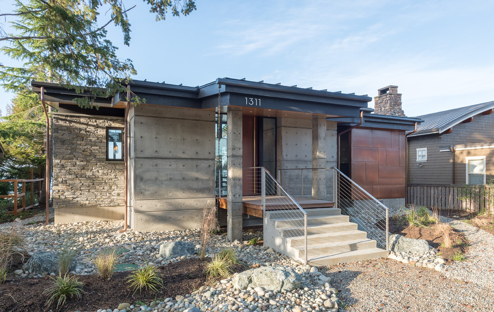 Small modern one-storey concrete grey house exterior in Seattle with a shed roof and a metal roof.