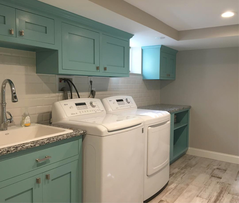 Photo of a large country single-wall utility room in Newark with a farmhouse sink, raised-panel cabinets, turquoise cabinets, granite benchtops, grey walls, painted wood floors, a side-by-side washer and dryer, multi-coloured floor and multi-coloured benchtop.