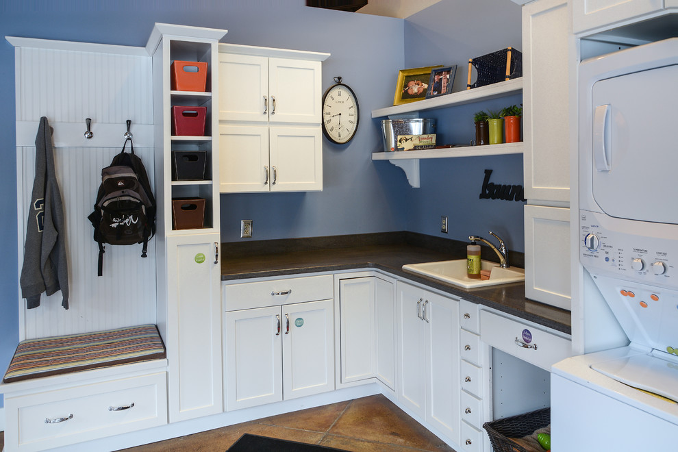 Kitchen - mid-sized transitional l-shaped concrete floor kitchen idea with a drop-in sink, shaker cabinets, white cabinets, solid surface countertops, blue walls and a stacked washer/dryer