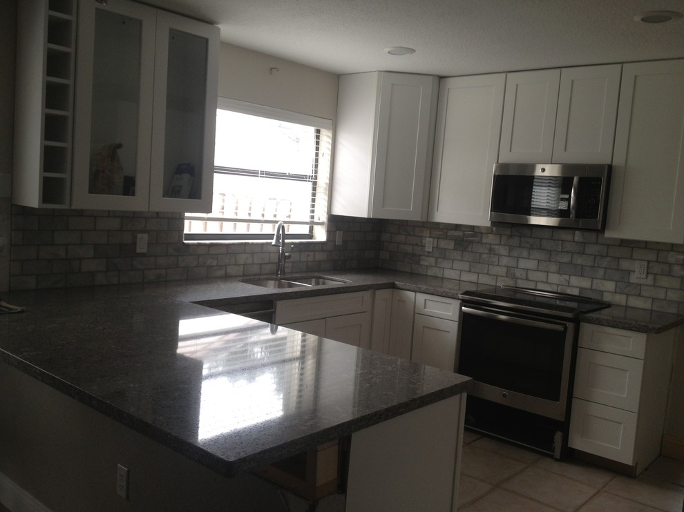 Mid-sized transitional u-shaped eat-in kitchen in Miami with an undermount sink, shaker cabinets, white cabinets, quartz benchtops, subway tile splashback, stainless steel appliances, porcelain floors and a peninsula.