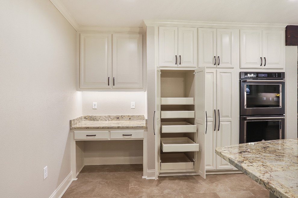 Photo of a large transitional galley open plan kitchen in New Orleans with a single-bowl sink, raised-panel cabinets, white cabinets, granite benchtops, white splashback, subway tile splashback, black appliances, porcelain floors, with island, beige floor and multi-coloured benchtop.