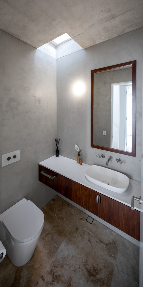 Réalisation d'un petit WC suspendu design en bois foncé avec un sol en travertin, un plan de toilette en terrazzo, un plan de toilette blanc et meuble-lavabo suspendu.