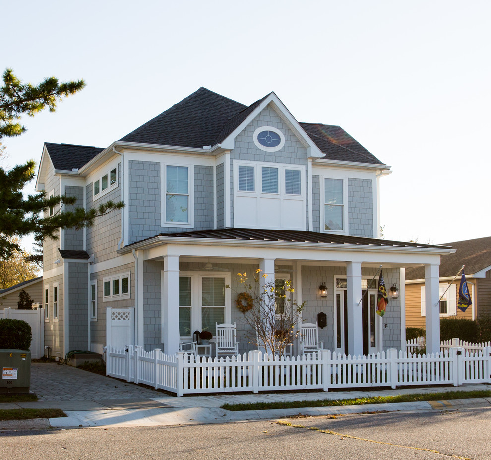 Photo of a beach style two-storey blue house exterior in Other with wood siding, a hip roof and a shingle roof.