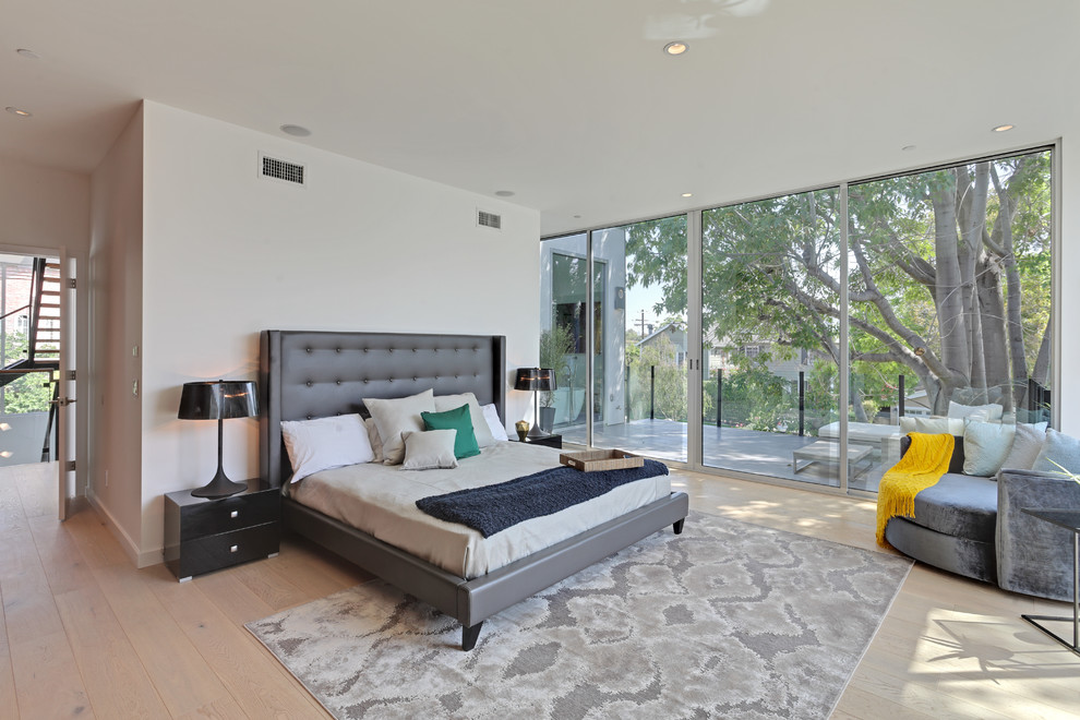 Contemporary bedroom in Los Angeles with white walls and light hardwood floors.