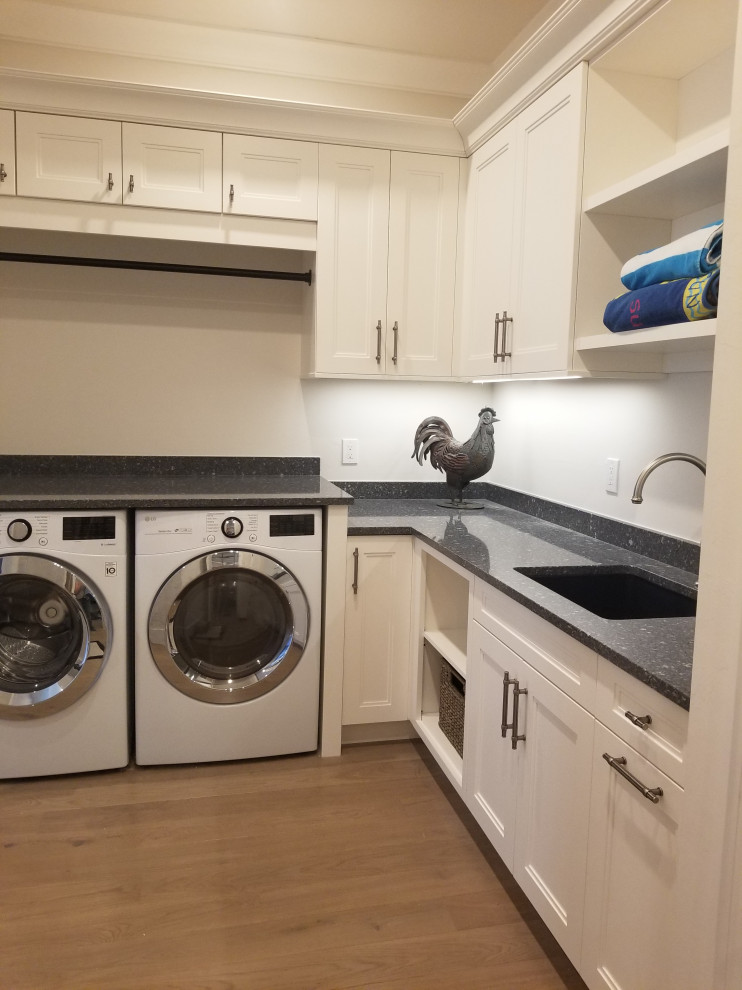 This is an example of a large transitional l-shaped utility room in Miami with an undermount sink, recessed-panel cabinets, white cabinets, quartz benchtops, beige walls, medium hardwood floors, an integrated washer and dryer, beige floor and blue benchtop.