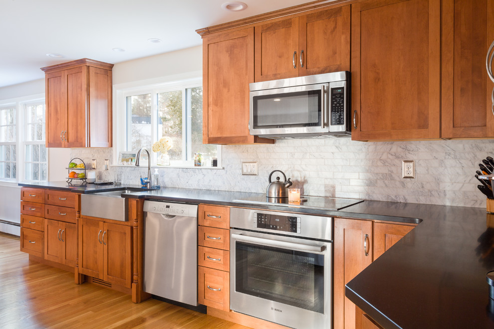 Example of a mid-sized transitional u-shaped medium tone wood floor eat-in kitchen design in Boston with a farmhouse sink, beaded inset cabinets, medium tone wood cabinets, marble countertops, gray backsplash, marble backsplash, stainless steel appliances, a peninsula and gray countertops