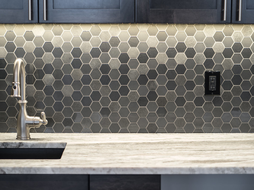 Design ideas for a mid-sized contemporary single-wall wet bar in Edmonton with a drop-in sink, recessed-panel cabinets, black cabinets, granite benchtops, grey splashback, glass tile splashback, laminate floors and brown floor.