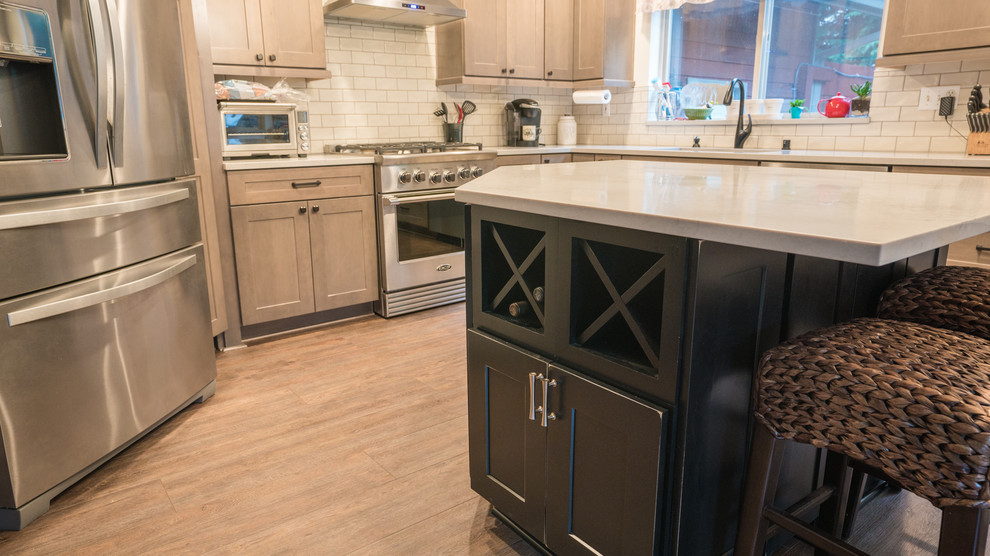 Large transitional l-shaped vinyl floor and brown floor open concept kitchen photo in Seattle with an undermount sink, recessed-panel cabinets, medium tone wood cabinets, quartz countertops, white backsplash, subway tile backsplash, stainless steel appliances, an island and white countertops