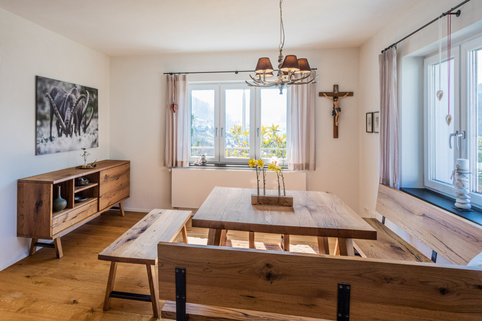 Exemple d'une petite salle à manger ouverte sur le salon montagne avec un mur blanc, un sol en bois brun, un poêle à bois, un manteau de cheminée en plâtre, un sol beige, un plafond en papier peint et du papier peint.