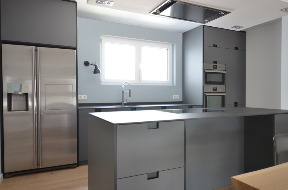 Photo of a mid-sized contemporary single-wall open plan kitchen in Frankfurt with a single-bowl sink, flat-panel cabinets, grey cabinets, blue splashback, stainless steel appliances, light hardwood floors and with island.