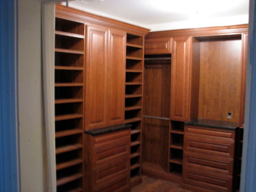 Large transitional gender-neutral walk-in wardrobe in New York with medium wood cabinets.