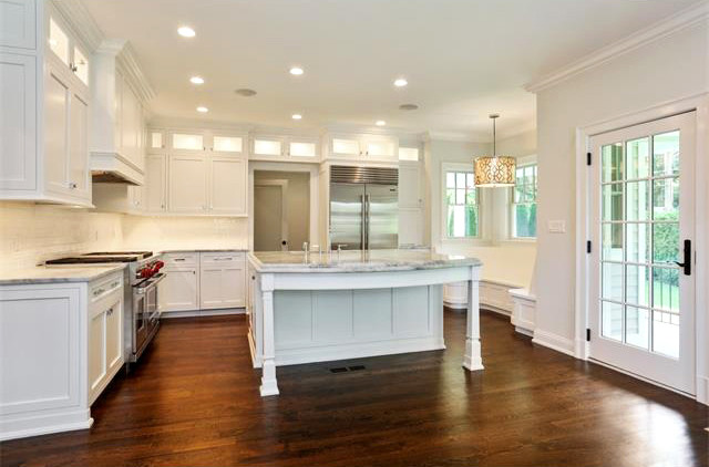 This is an example of a large traditional l-shaped eat-in kitchen in New York with a single-bowl sink, white cabinets, marble benchtops, white splashback, stainless steel appliances, dark hardwood floors, with island, shaker cabinets and subway tile splashback.