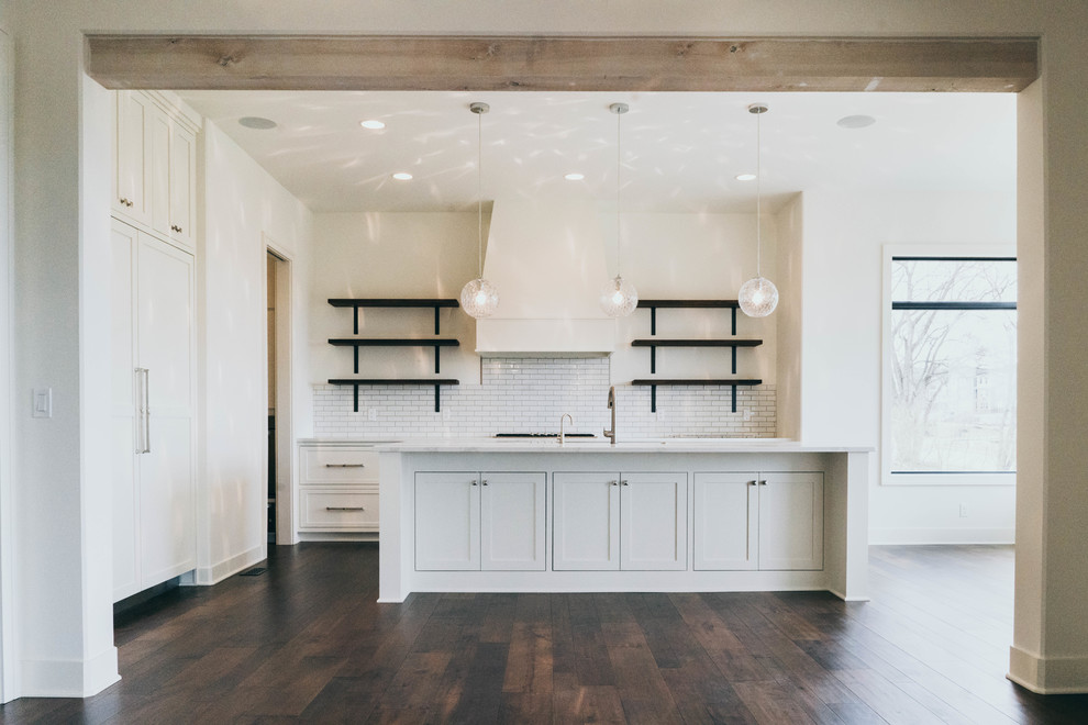 Transitional dark wood floor enclosed kitchen photo in Omaha with a farmhouse sink, shaker cabinets, white cabinets, quartz countertops and an island