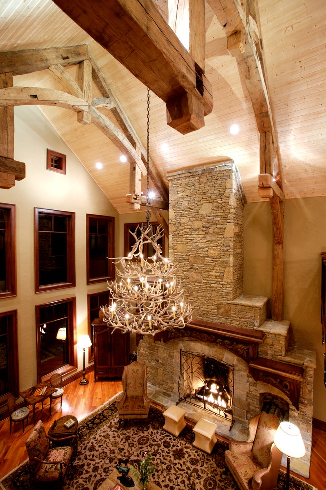 Inspiration for an expansive country formal open concept living room in Other with beige walls, medium hardwood floors, a standard fireplace, a stone fireplace surround and no tv.