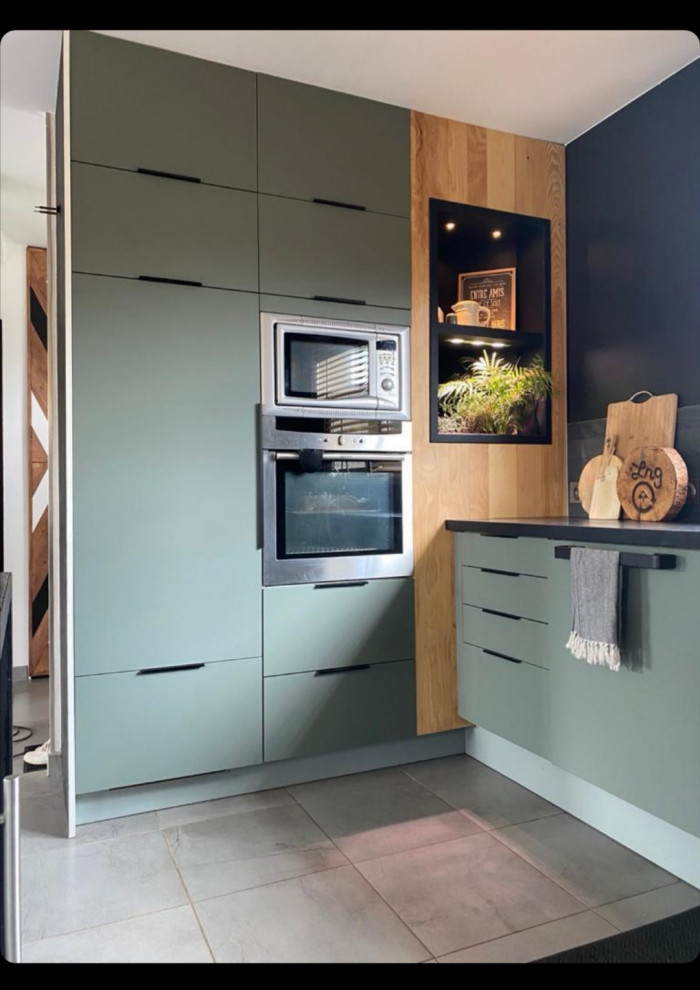 Photo of a mid-sized modern u-shaped eat-in kitchen in Other with an undermount sink, beaded inset cabinets, green cabinets, concrete benchtops, black splashback, stone slab splashback, stainless steel appliances, no island, grey floor and black benchtop.