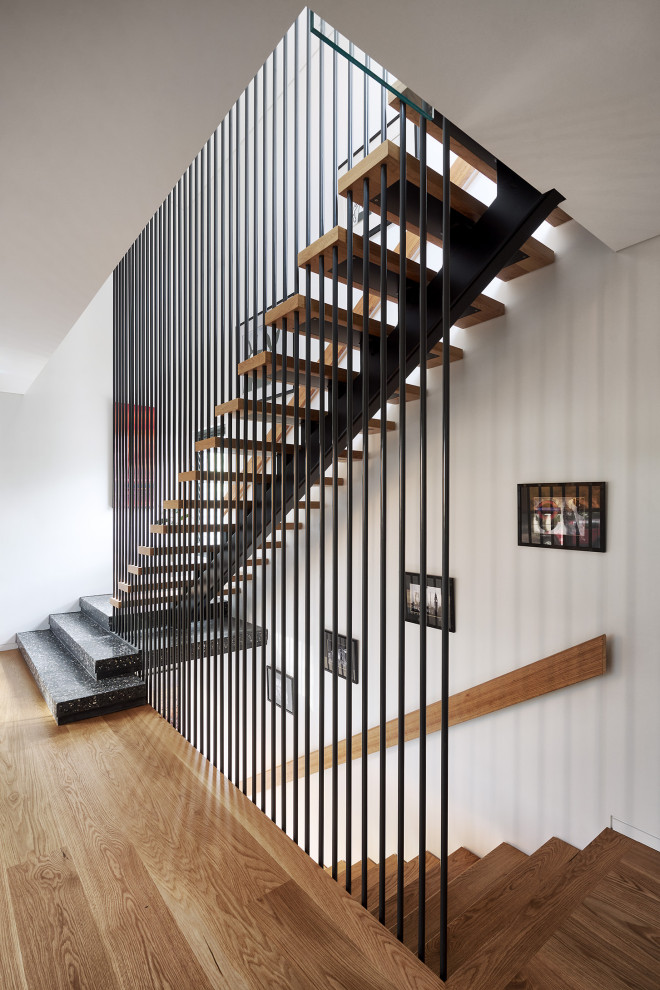 Diseño de escalera recta actual sin contrahuella con escalones de madera y barandilla de metal