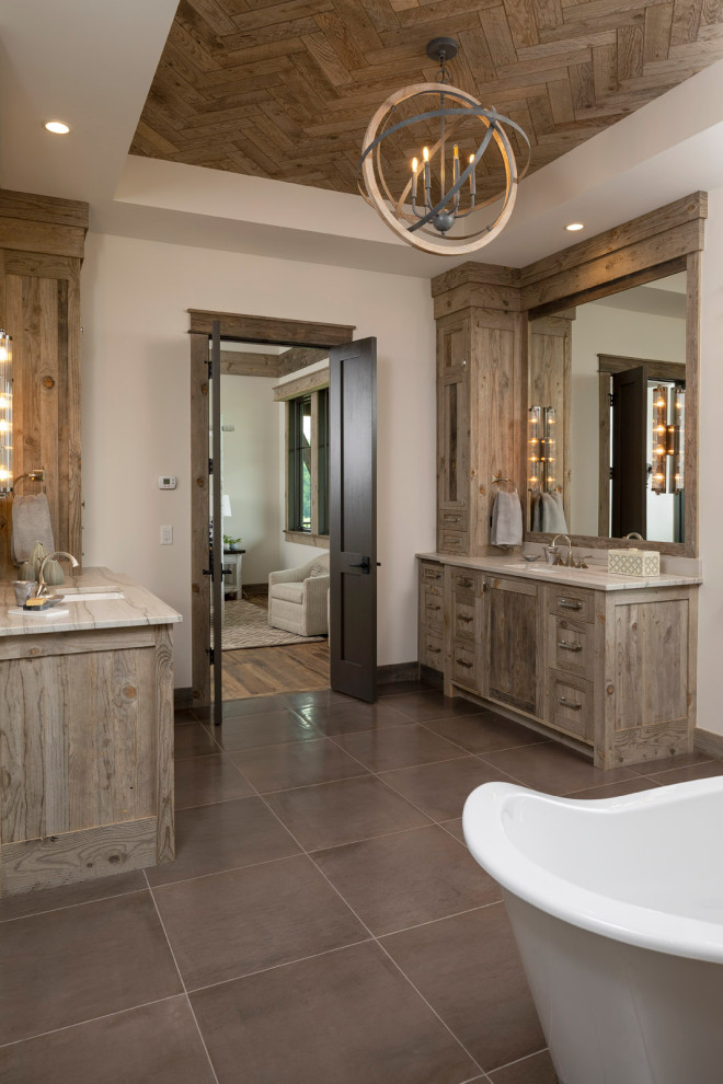 This is an example of a large country master bathroom in Minneapolis with recessed-panel cabinets, grey cabinets, a freestanding tub, an open shower, gray tile, ceramic tile, grey walls, ceramic floors, an undermount sink, marble benchtops, grey floor, an open shower, multi-coloured benchtops, a double vanity, a built-in vanity and wood.
