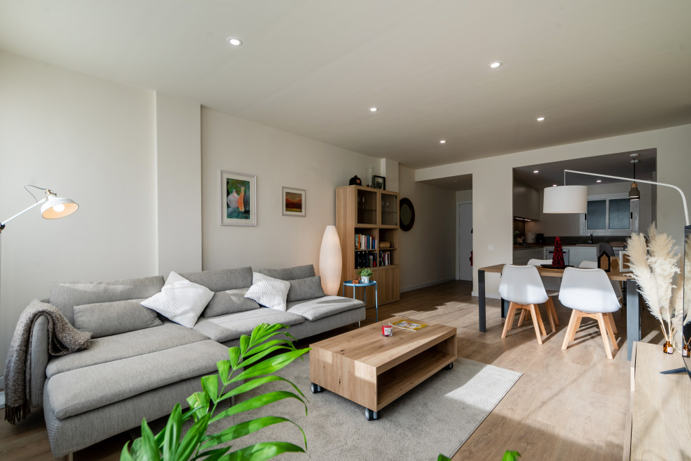 Modelo de sala de estar con barra de bar abierta minimalista de tamaño medio con paredes beige, suelo de madera clara, televisor independiente, suelo marrón y alfombra