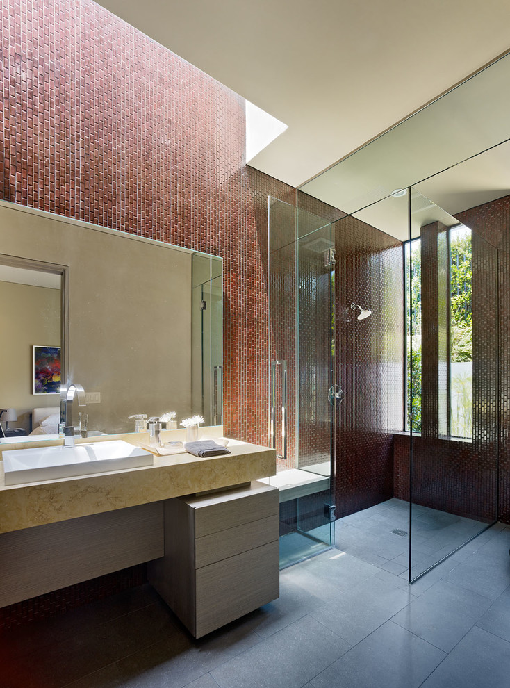 Photo of a large contemporary master bathroom in Los Angeles with flat-panel cabinets, light wood cabinets, a curbless shower, brown tile, a hinged shower door, ceramic tile, red walls, light hardwood floors, a vessel sink and concrete benchtops.