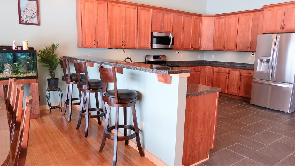 This is an example of a large transitional u-shaped eat-in kitchen in Other with a drop-in sink, shaker cabinets, light wood cabinets, granite benchtops, stainless steel appliances, vinyl floors and a peninsula.