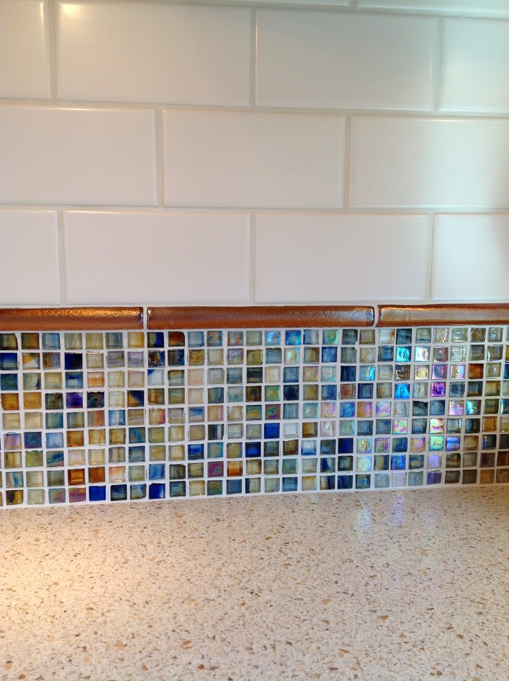 Eat-in kitchen - mid-sized transitional u-shaped medium tone wood floor eat-in kitchen idea in San Diego with solid surface countertops, an integrated sink, raised-panel cabinets, medium tone wood cabinets, multicolored backsplash, mosaic tile backsplash, stainless steel appliances and a peninsula